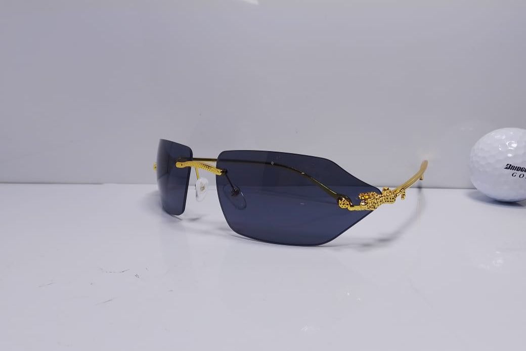 Sunglasses with gold frame and dark lenses on a white surface