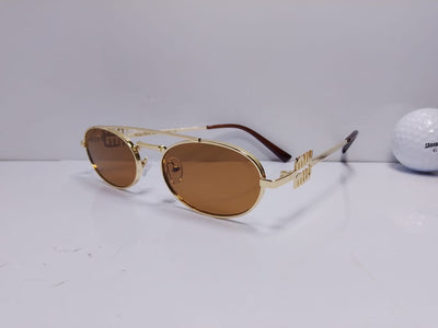Gold-framed sunglasses with brown lenses on a white surface