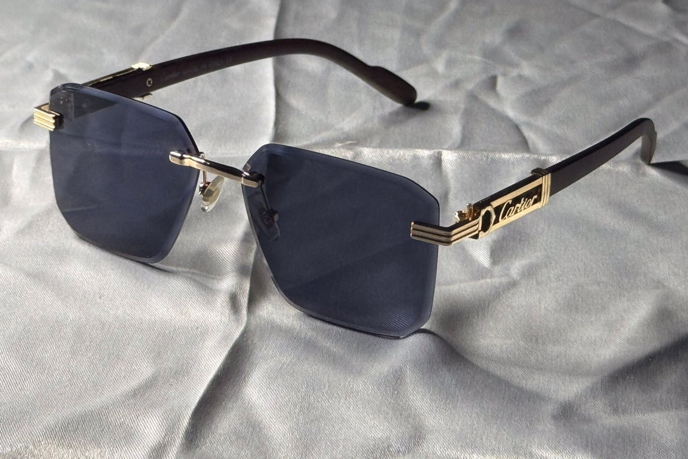 Sunglasses with gold frame and dark lenses on a textured gray surface