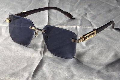 Sunglasses with gold frame and dark lenses on a textured gray surface
