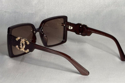 Brown sunglasses with gold accents on a light gray background
