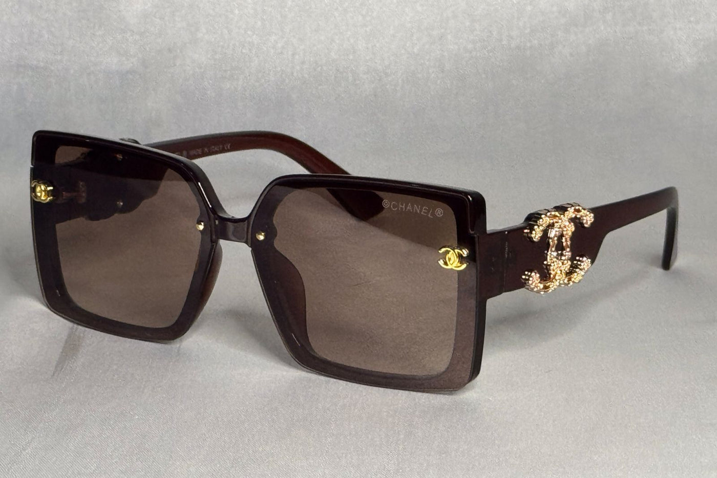 Chanel sunglasses with gold accents on a light gray background