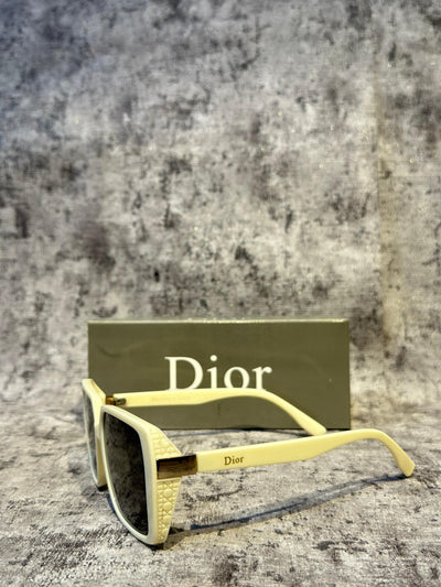 Yellow sunglasses with 'Dior' branding on a textured surface