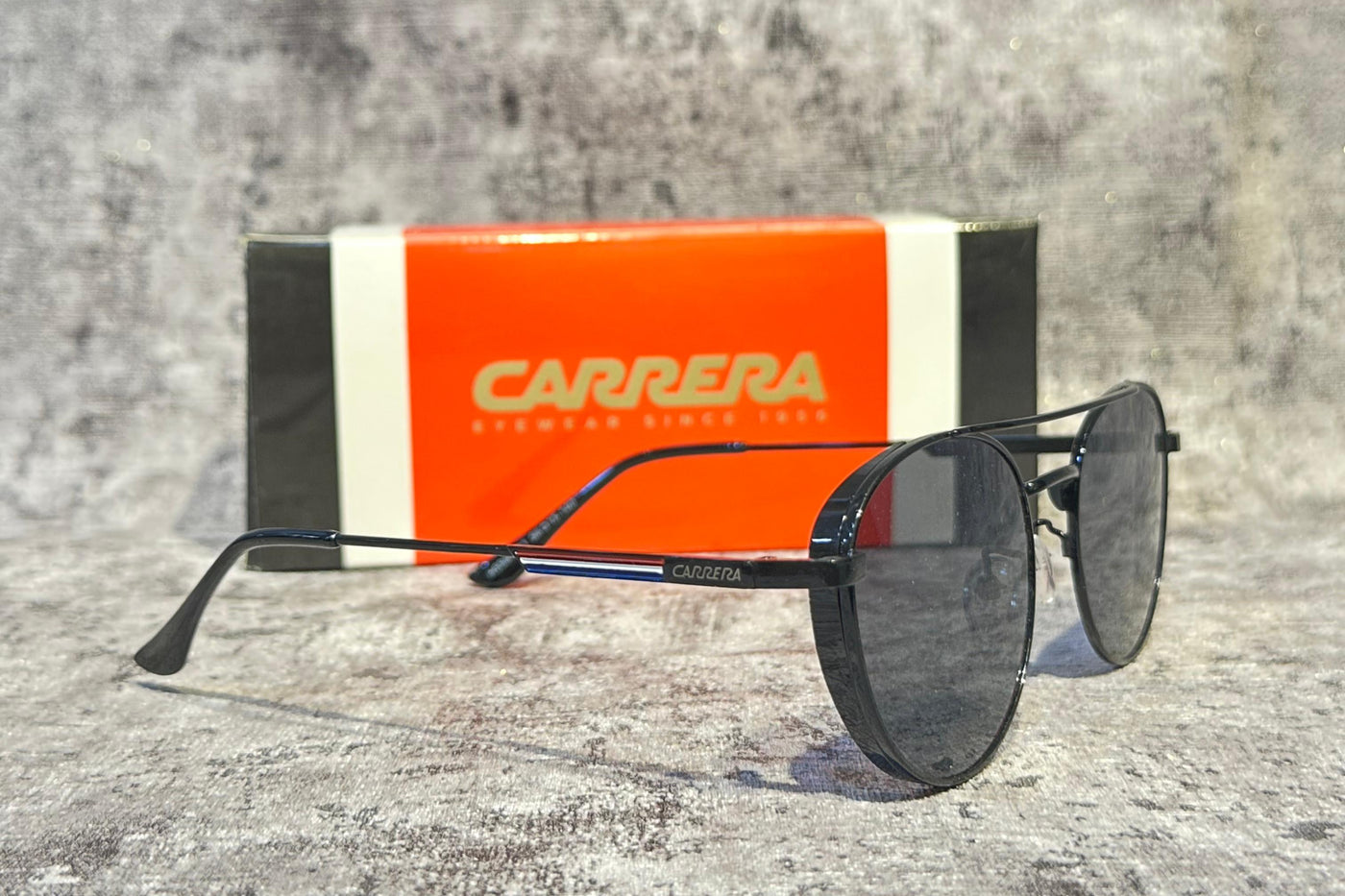 Carrera sunglasses with orange and black box on a gray surface