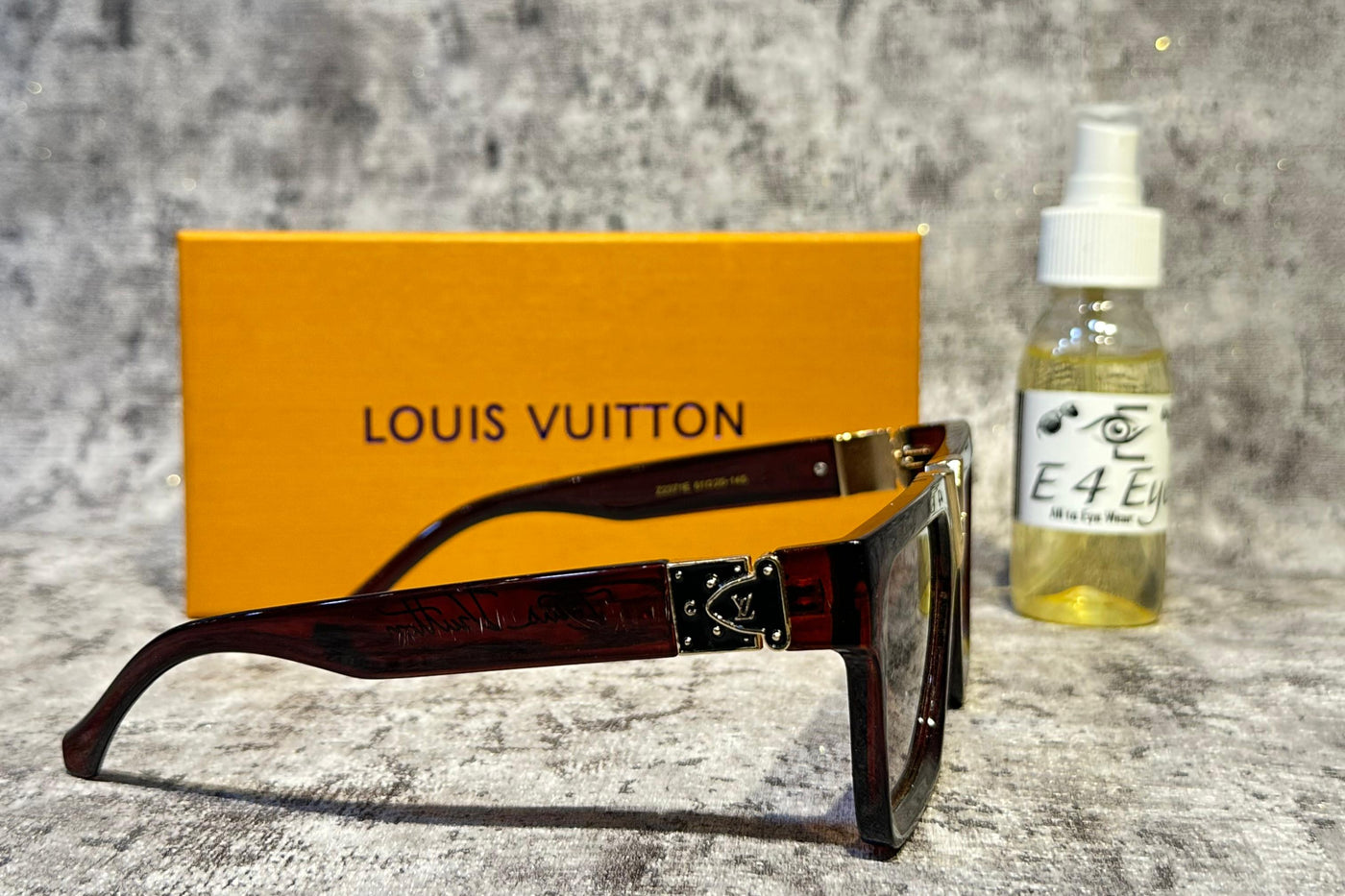 Louis Vuitton sunglasses with a bottle and box on a textured surface