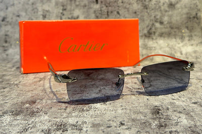 Sunglasses with a Cartier box on a textured surface