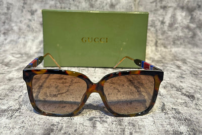 Sunglasses with a Gucci case on a textured gray surface