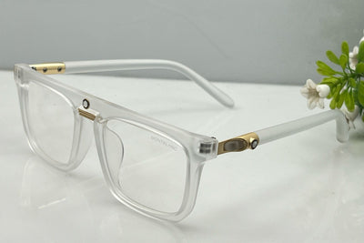 Clear eyeglasses with gold accents on a light surface with a blurred background